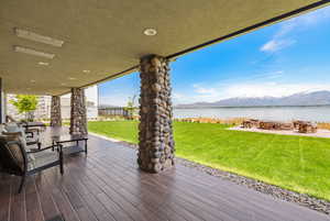 Covered deck with a fire pit, a yard, fence, and a water and mountain view