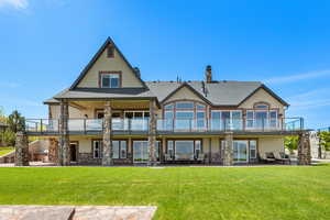 Rear view of property featuring a patio area, a lawn, a balcony, and stucco siding