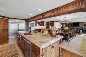 Kitchen featuring wood-type flooring, light stone counters, stainless steel appliances, and a sink