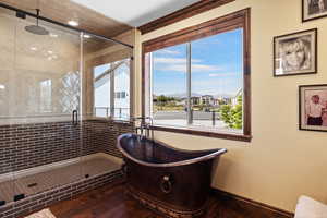 Full bathroom featuring a freestanding tub, a stall shower, wood finished floors, and baseboards