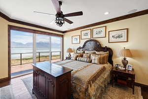 Bedroom with baseboards, wood finished floors, access to outside, crown molding, and a water and mountain view