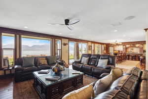 Living area featuring recessed lighting, ceiling fan with notable chandelier, dark wood-style flooring, visible vents, and a water and mountain view