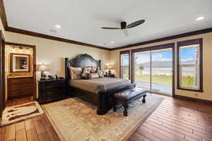 Bedroom with light wood-type flooring, access to exterior, a water view, and ornamental molding