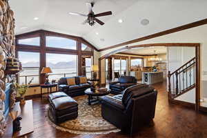 Living area with arched walkways, lofted ceiling, a fireplace, ornamental molding, and dark wood finished floors