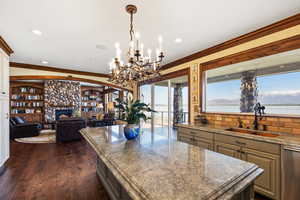 Kitchen with stainless steel dishwasher, dark wood-style flooring, a sink, and crown molding