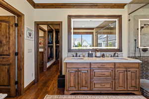 Bathroom featuring a tile shower, a sink, and wood finished floors