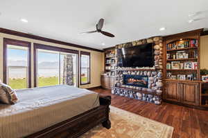 Bedroom featuring ornamental molding, a stone fireplace, dark wood-type flooring, and recessed lighting