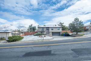 View of front of house featuring a mountain view, driveway, an attached garage, and fence