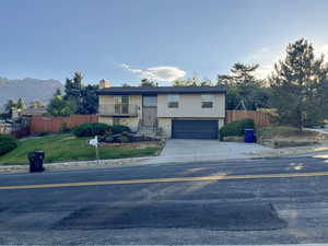 Split foyer home featuring a mountain view, a garage, brick siding, fence, and driveway