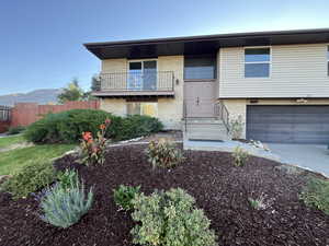 Raised ranch with a mountain view, brick siding, fence, and a balcony