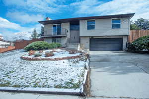 Bi-level home featuring brick siding, fence, a balcony, and an attached garage