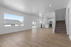 Unfurnished living room with light wood-type flooring, stairs, baseboards, and recessed lighting