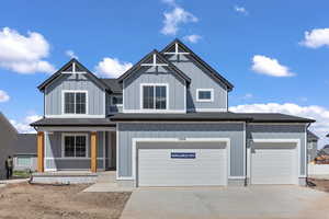 View of front of property with board and batten siding, concrete driveway, roof with shingles, and a porch