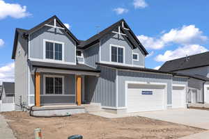 View of front of house with a shingled roof, concrete driveway, an attached garage, covered porch, and board and batten siding