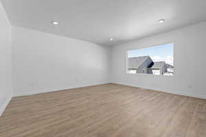 Empty room featuring a textured ceiling, baseboards, and wood finished floors