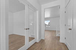 Corridor with french doors, visible vents, baseboards, and wood finished floors