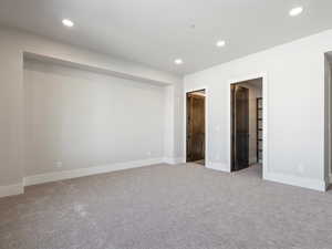 Unfurnished bedroom featuring recessed lighting, a walk in closet, carpet flooring, and baseboards