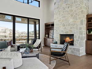 Living room with a towering ceiling, a mountain view, a stone fireplace, wood finished floors, and baseboards