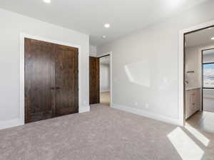 Unfurnished bedroom with recessed lighting, a closet, light carpet, and baseboards