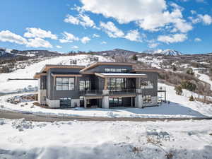 Snow covered property featuring a balcony, a garage, and a mountain view