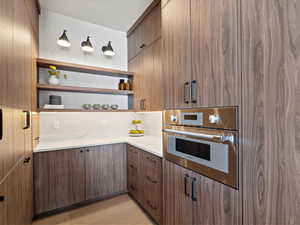 Kitchen with open shelves, light stone countertops, oven, and light wood-style floors