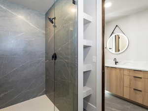 Bathroom featuring tiled shower and vanity