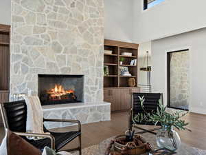 Living room featuring a fireplace, a high ceiling, and wood finished floors