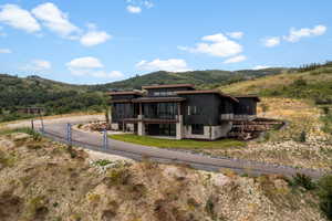 Rear view of property featuring a mountain view, a balcony, driveway, and a metal roof
