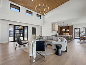 Living room with recessed lighting, an inviting chandelier, light wood-type flooring, wooden ceiling, and baseboards