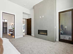 Bedroom featuring carpet, a fireplace, a high ceiling, and ensuite bathroom