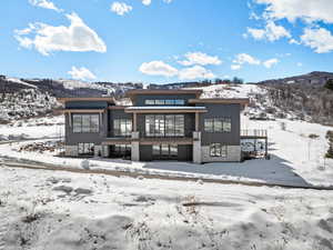 Snow covered back of property with a mountain view