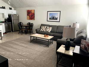 Living room with light tile patterned floors, and vaulted ceiling