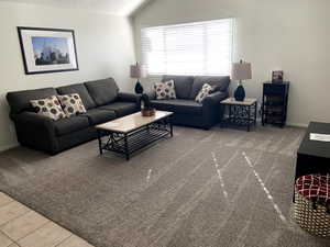 Living room featuring vaulted ceiling,, carpet, and tile patterned flooring