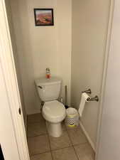 Bathroom featuring baseboards, toilet, and tile patterned floors