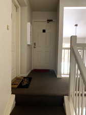 Public interior entry space featuring carpet, baseboards, and an upstairs landing