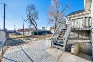 View of patio featuring stairway to basement, fence, and a wooden deck