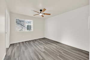 Master bedroom featuring shiplap wall, ceiling fan, wood finished floors, and walk in closet