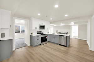 Kitchen featuring stainless steel appliances, a sink, light wood-style floors, quartz countertops, and gray cabinets