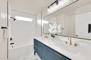 Master Bathroom with double vanity, marble finish floor, bathtub / shower combination, and a large mirror.