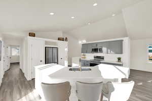 Kitchen with lofted ceiling, an island with sink, appliances with stainless steel finishes, gray cabinetry, and a sink and double pantry