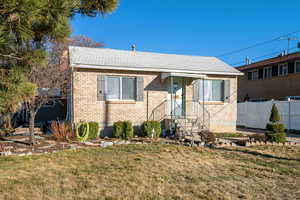 Bungalow-style house featuring a front yard, brick siding, and fence