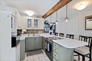 Kitchen with a breakfast bar, electric stove, tasteful backsplash, beamed ceiling, and a peninsula