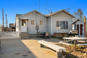 Back of property featuring an outbuilding, entry steps, outdoor dining space, a storage unit, and a patio area