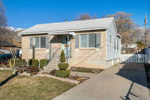 Bungalow featuring brick siding, roof with shingles, and fence