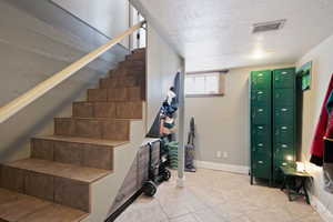 Staircase with baseboards, visible vents, and a textured ceiling