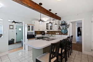 Kitchen with light tile patterned floors, light countertops, appliances with stainless steel finishes, a peninsula, and a kitchen bar