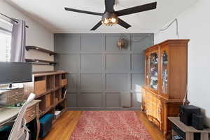 Interior space with light wood-type flooring, a ceiling fan, and a decorative wall