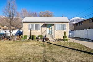 Bungalow-style house with brick siding, a front yard, and fence