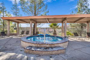 View of pool with fence, a community hot tub, and a patio