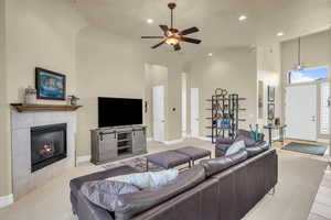 Living area featuring recessed lighting, a towering ceiling, a tiled fireplace, a ceiling fan, and baseboards